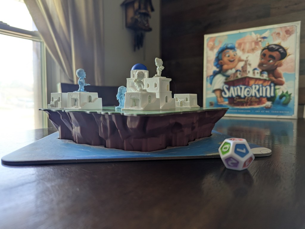 The game of Santorini in mid play, with the dice nearby.
