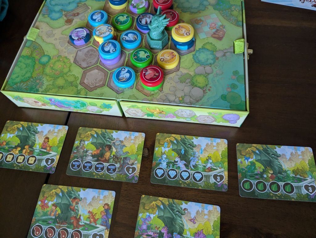 Flamecraft Duals set up with the Fountain module. There's a green dragon miniature on the board, as well as the four-in-a-row scoring cards laid out next to the board.