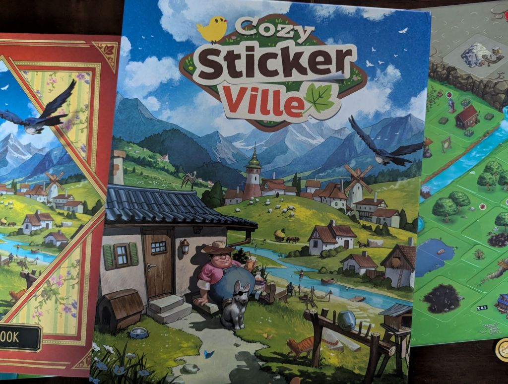 the box of cozy stickerville atop its components