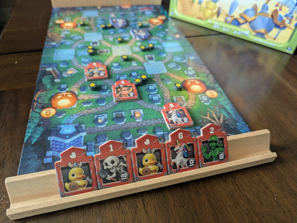 A close up of the wooden rack where players hold their tokens for Toy Battle. The red player has two ducks, a skeleton, a general, and a skeleton.