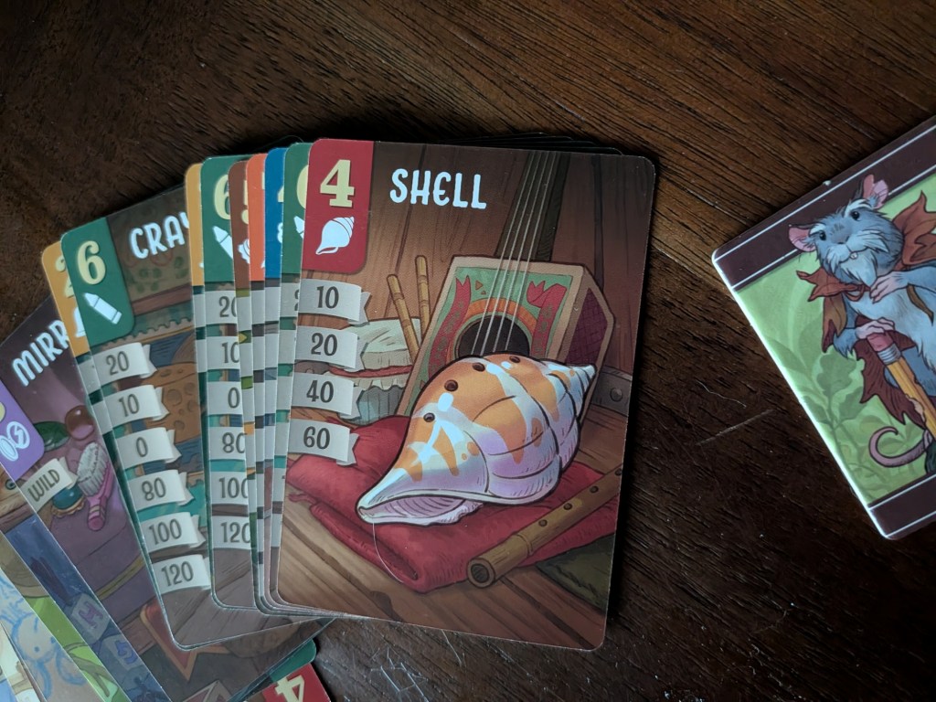 A spread of Trinket Trove cards. On top, a Shell card sits, worth 60 points for a full set of four.