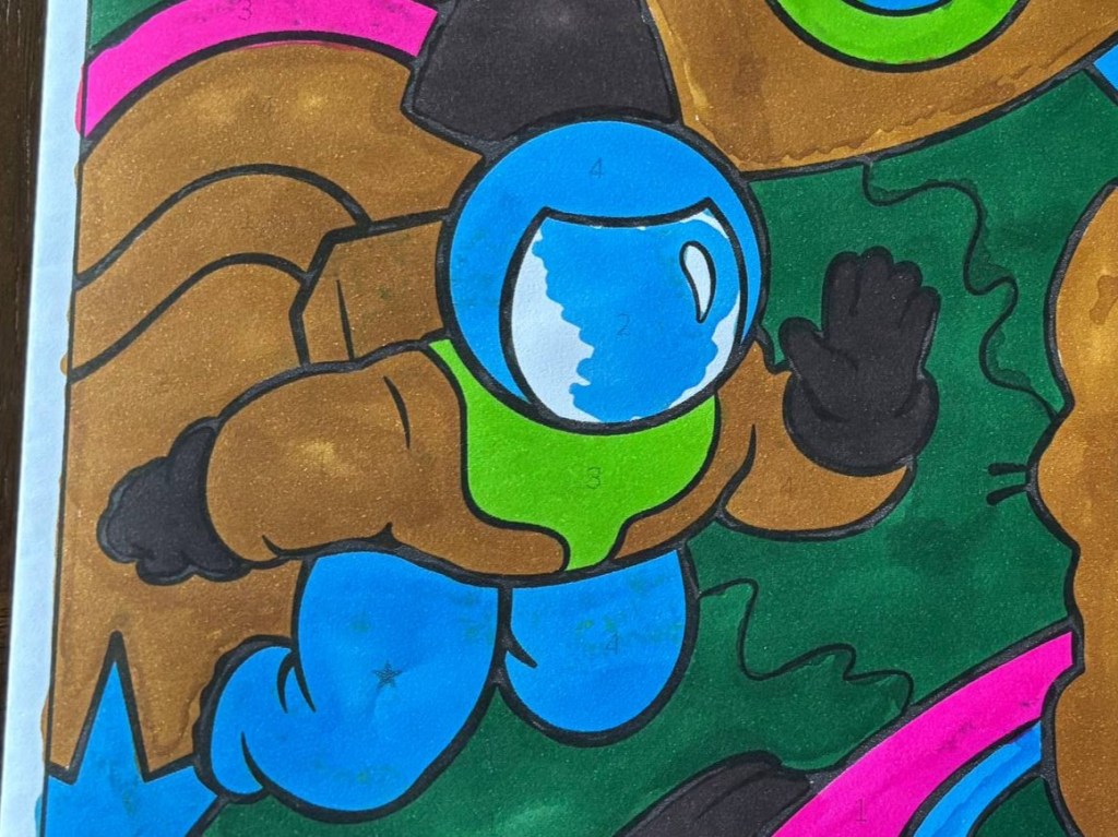 a close up of a finished coloring book page from Color Jam. it's an astronaut wearing blue and green and brown. he looks vaguely like he's styled after a minecraft dirt block.